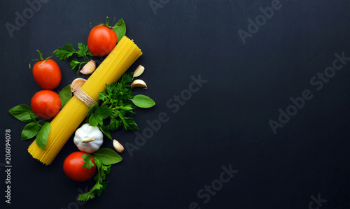 Ingredients for spaghetti with tomato sauce on dark wooden background. Italian healthy food background. Flat- lay.