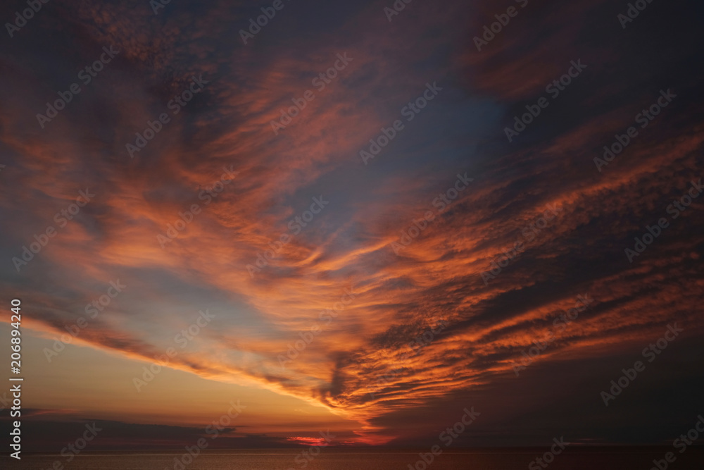Zachód słońca nad morzem z pomarańczowymi chmurami