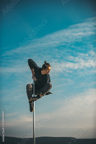 Wallpaper Mural Athletic man makes beautiful athletic, acrobatic elements on a portable pylon on the blue sky background Torontodigital.ca