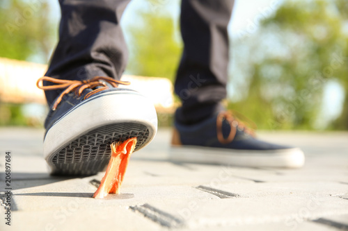 Obraz na plátně Man stepping in chewing gum on sidewalk. Concept of stickiness