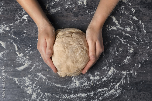 Young woman kneading dough at table, top view