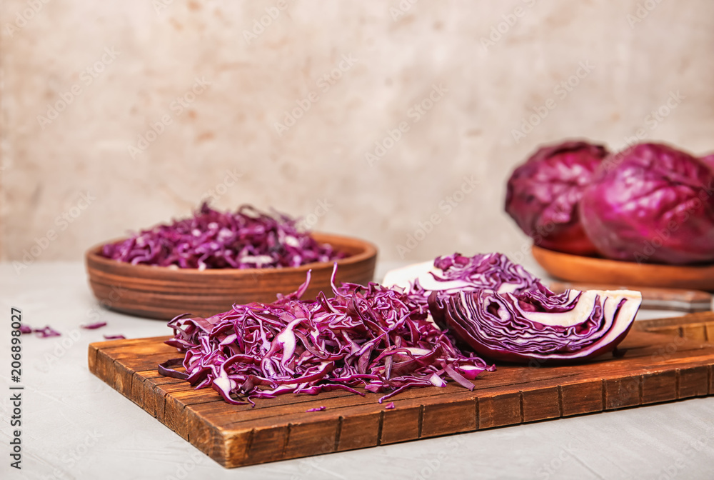 Wooden board with chopped purple cabbage on table