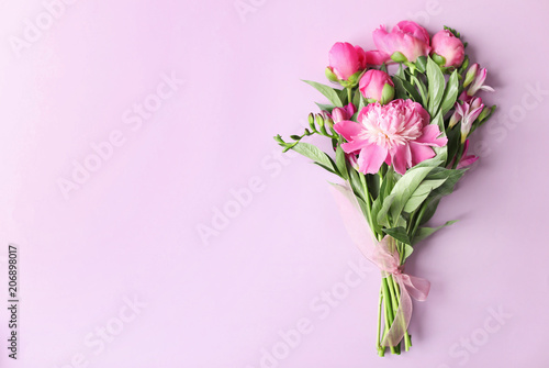 Bouquet of beautiful peony flowers on color background, top view