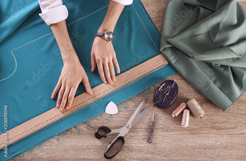Tableau sur toile Tailor working with cloth at table in atelier, top view