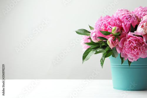 Fototapeta Naklejka Na Ścianę i Meble -  Bucket with beautiful peony flowers on table against light background