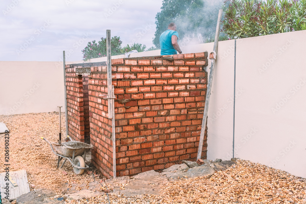 Part build construction of a brick shed. A bricklayer can be seen working  creating dust. the construction is a small brick shed or outhouse Stock  Photo | Adobe Stock