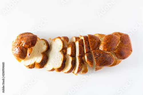 cut braided bread sprinkled with poppy seeds, isolated on white. copy space photo