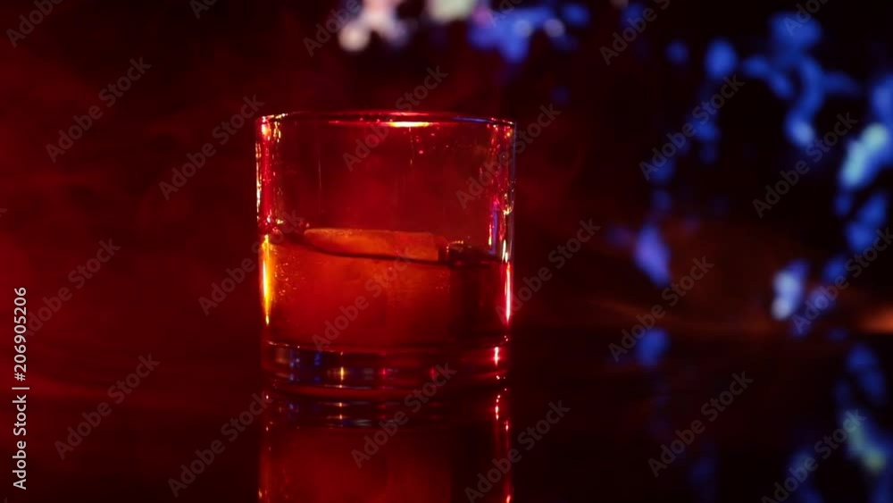 Selective focus pure whisky with ice cube inside whisky glass on dark foggy background alcohol drink concept. Close up. Slider shot. Slow motion Selective focus pure whisky with ice cube inside whisky glass on dark foggy background alcohol drink concept. Close up. Slider shot. Slow motion