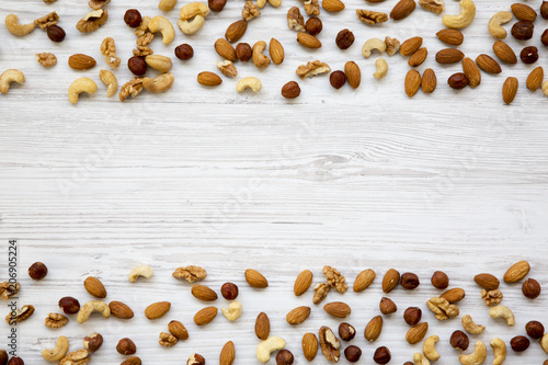 Assorted mixed nuts (cashew, hazelnuts, walnuts, almonds) on white wooden background, top view. Flat lay. Copy space.
