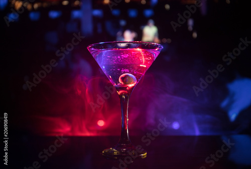 glass with martini with olive inside. Close up view of glass with club drink on dark foggy toned background. Club drink concept © zef art