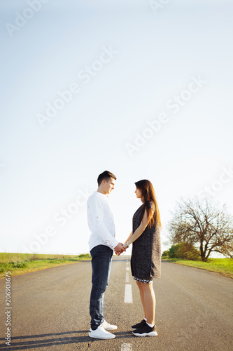 young, happy, loving couple standing on the road holding hands and looking at each other, advertising and inserting text