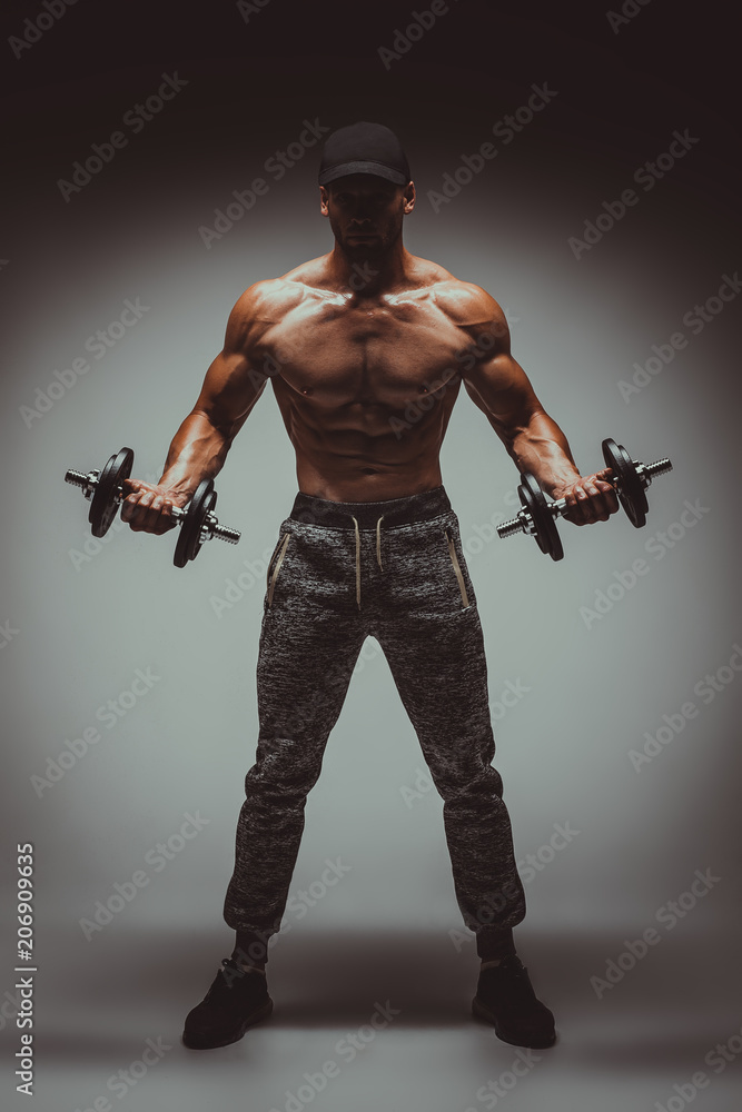 Strong young man bodybuilder performing exercise for biceps with heavy weights in both hands. Concept Gym Life Style.Toned Image. Strong young man bodybuilder performing exercise for biceps with heavy weights in both hands. Concept Gym Life Style.Toned Image.