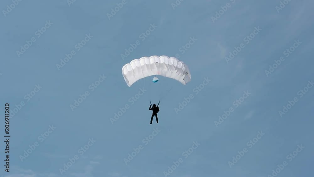 A man parachutes down to the ground. Parachute flight. The view from the ground A man parachutes down to the ground. Parachute flight. The view from the ground