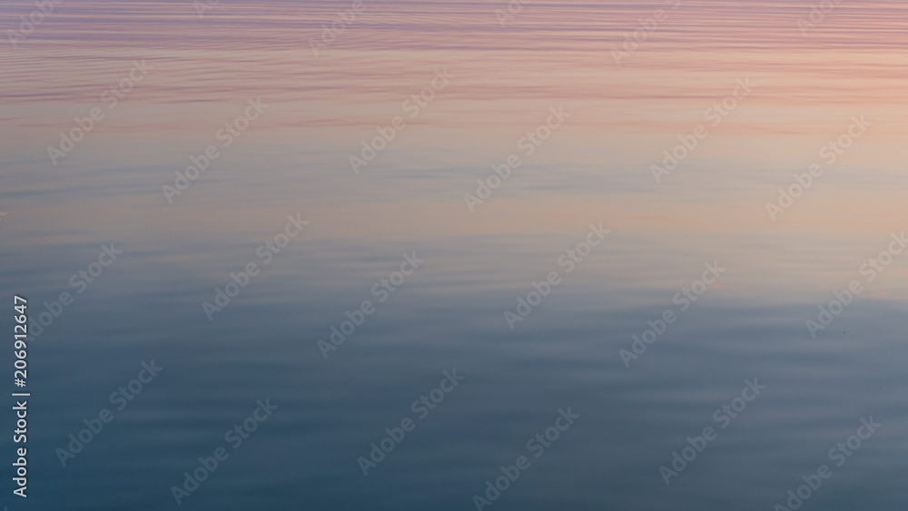 Beautiful sunset reflected in calm mirrored water surface.
