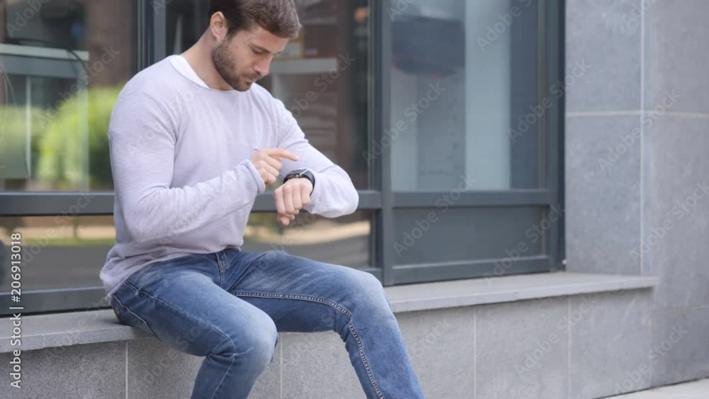 Handsome Man Sitting Outside Office Using Smartwatch for Browsing Handsome Man Sitting Outside Office Using Smartwatch for Browsing