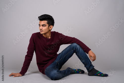 Young Indian man against gray background