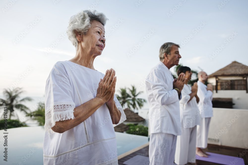 Group of seniors practicing yoga by the pool Group of seniors practicing yoga by the pool