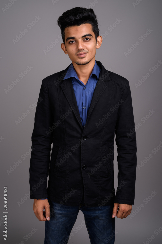 Fototapeta premium Young Indian businessman against gray background