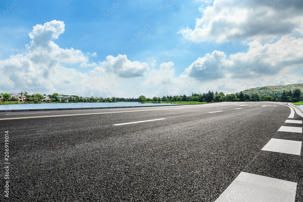 Fototapeta premium Asphalt road and apartment building with cloud landscape in the city suburbs