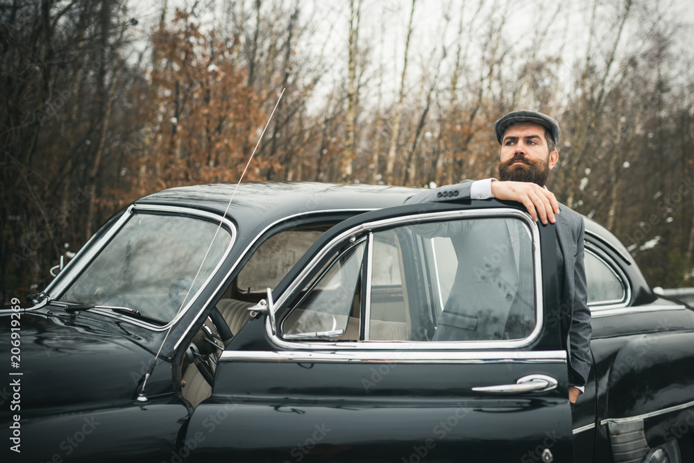 Escort man or security guard. Bearded man in car. Call boy in vintage auto. Retro collection car and auto repair by mechanic driver. Travel and business trip or hitch hiking
