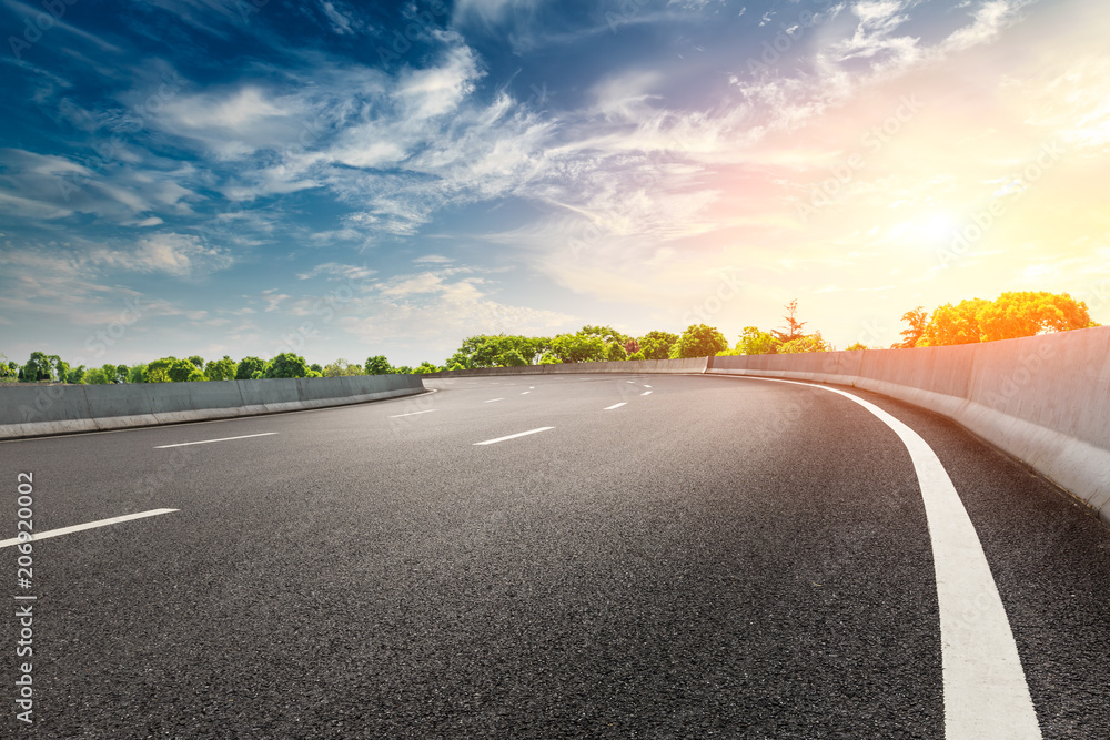 Fototapeta premium Empty asphalt road and woods landscape at sunset