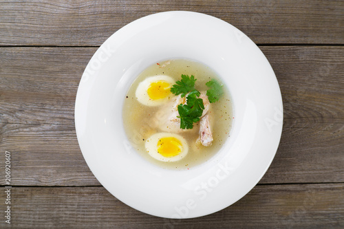 Tasty hot homemade dinner, diet food, healthy delicious meals. Meat broth with chicken meat, egg and parsley in a white bowl, bouillon with croutons