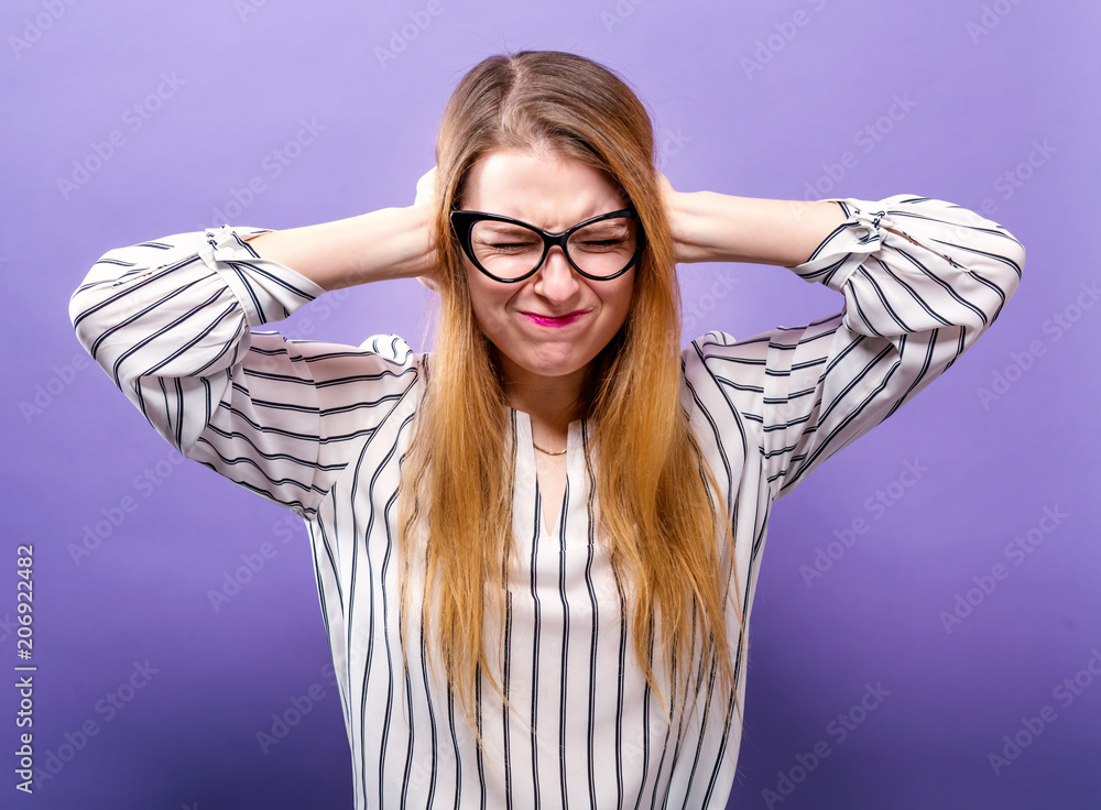 Young woman blocking her ears on a solid background Young woman blocking her ears on a solid background