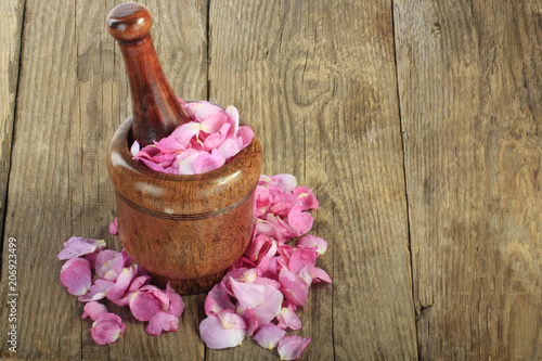 petals of rose in martar on wooden background photo