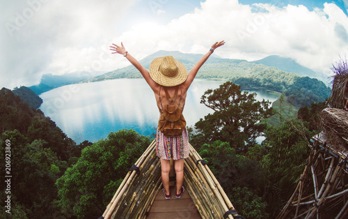 Happy female hiker standing on a cliff with her arms up in the air feeling free photo