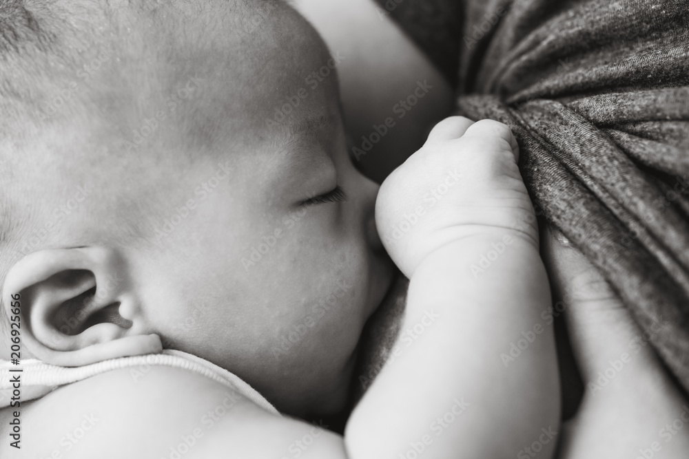 Baby feeds on mother's breasts milk in black and white tone. Baby feeds on mother's breasts milk in black and white tone.