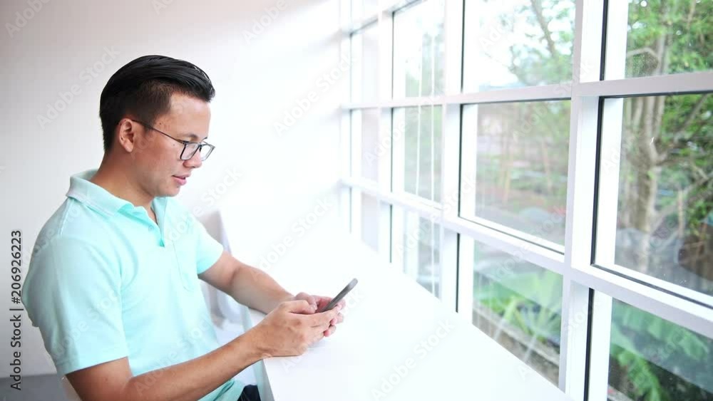 Casual business man working in coffeeshop. Young asian man sitting in coffee shop using his mobile phone. Casual business man working in coffeeshop. Young asian man sitting in coffee shop using his mobile phone.