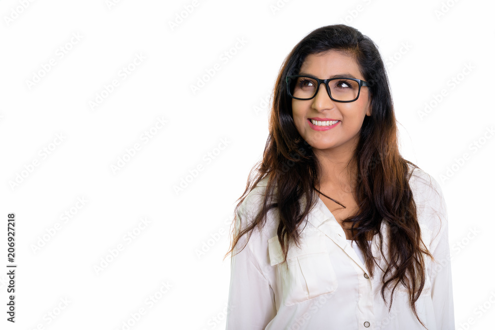 Studio shot of young happy Persian woman smiling and thinking wi Studio shot of young happy Persian woman smiling and thinking wi