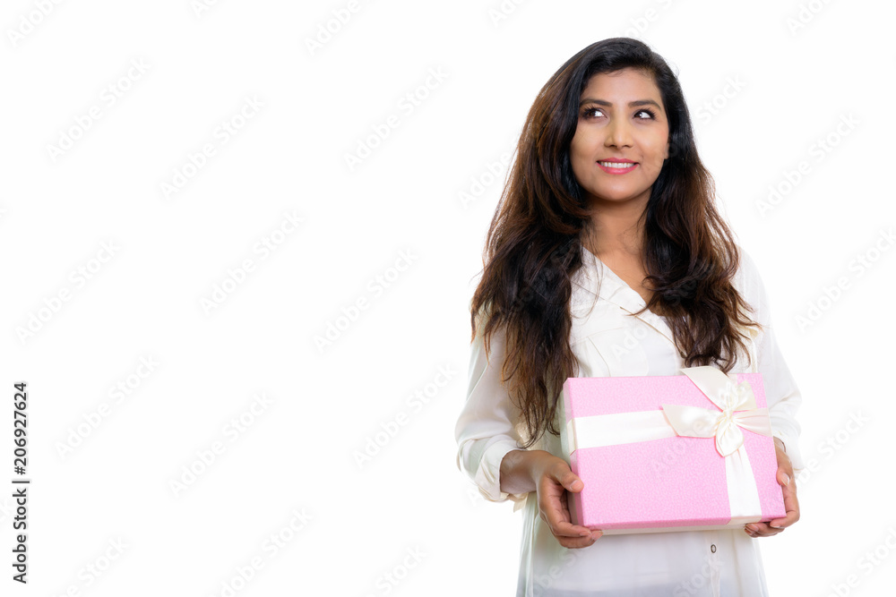 Studio shot of young happy Persian woman smiling and thinking wh Studio shot of young happy Persian woman smiling and thinking wh