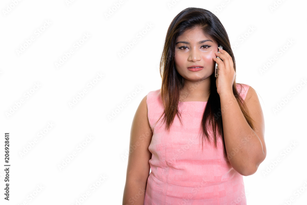 Studio shot of young fat Persian teenage girl talking on mobile Studio shot of young fat Persian teenage girl talking on mobile