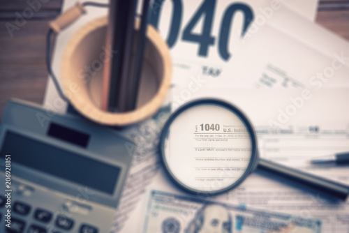 magnifying glass with tax form 1040 and calculator,Tax time concept selective focus effect