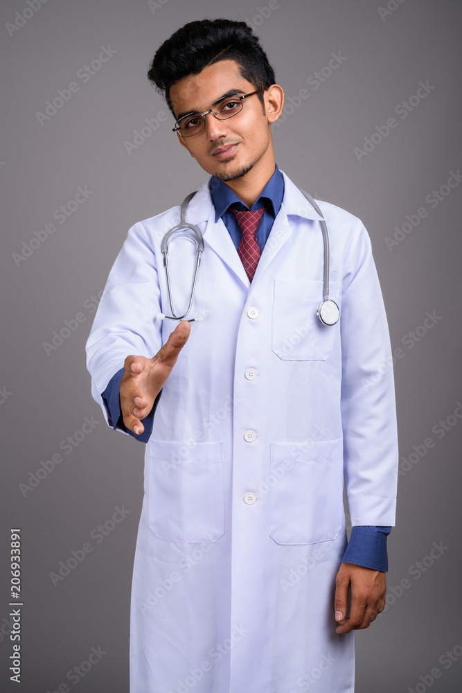 Young Indian man doctor against gray background Young Indian man doctor against gray background