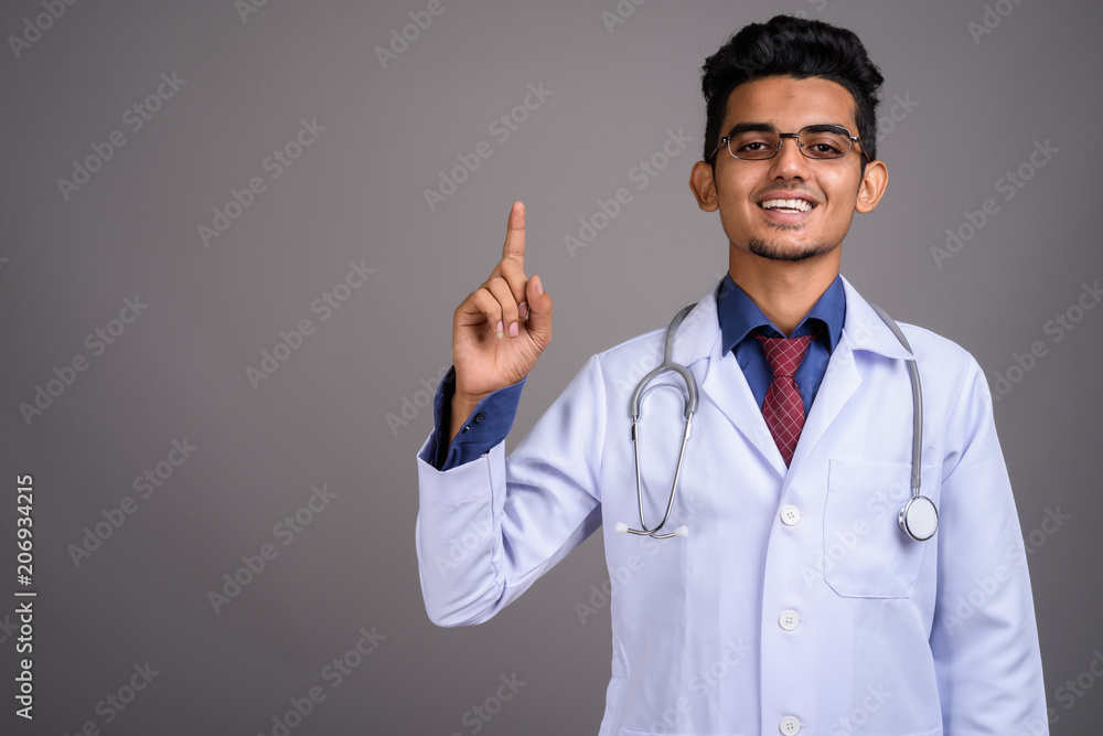 Young Indian man doctor against gray background Young Indian man doctor against gray background