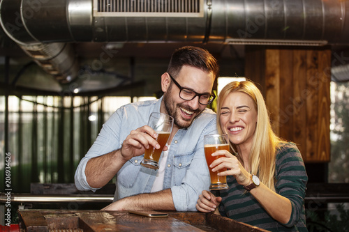 Foto Young couple looking each other in local pub with glass of beer