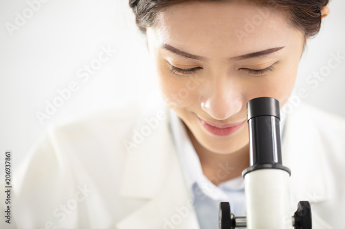 female medical or scientific researcher watching the microscope