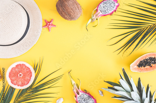 Summer composition. Tropical palm leaves, hat, pineapple, coconut, sea shells on yellow background. Summer concept. Flat lay, top view, copy space