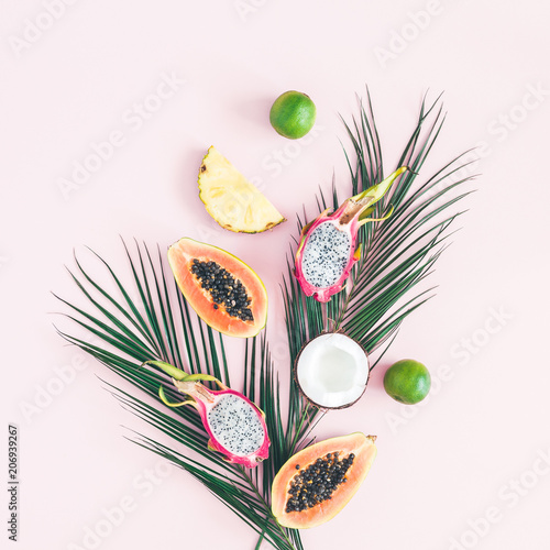 Summer fruits. Tropical palm leaves, pineapple, coconut, papaya, dragon fruit, orange on pastel pink background. Flat lay, top view, square