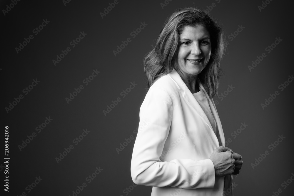 Mature beautiful businesswoman against gray background in black 
