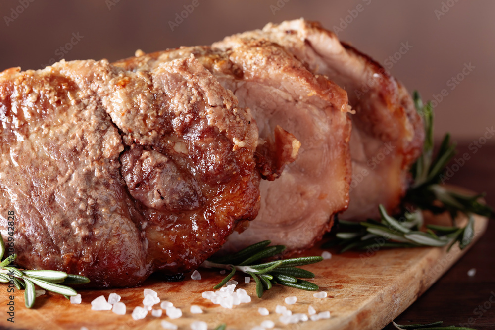 Oven-baked pork with rosemary and spices on a wooden table.