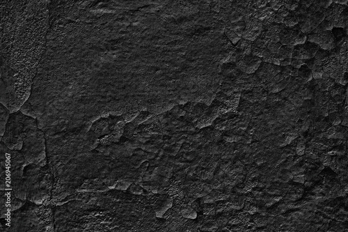 Gloomy background of old black wall with weathered cracked paint
