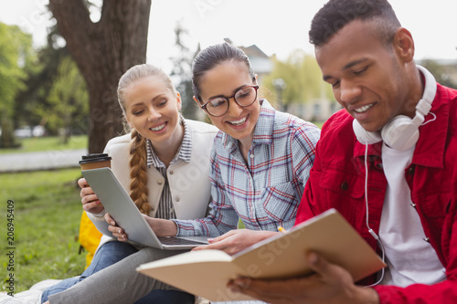 Excellent notes. Young smiling fellow feeling proud while sharing his excellent notes with his pretty friends