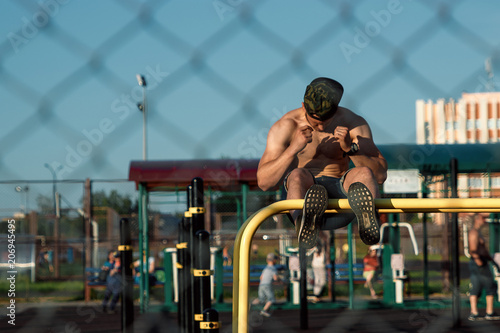 Young man doing exercise on the press on the sports field, athlete, outdoor training in the city copy space