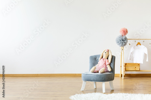 Empty wall, seat with a rabbit and hanger with pompoms and T-shirt. Place your product