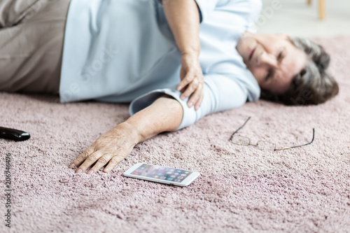 Quadro em tela Close-up of senior woman with heart attack and smartphone on the floor
