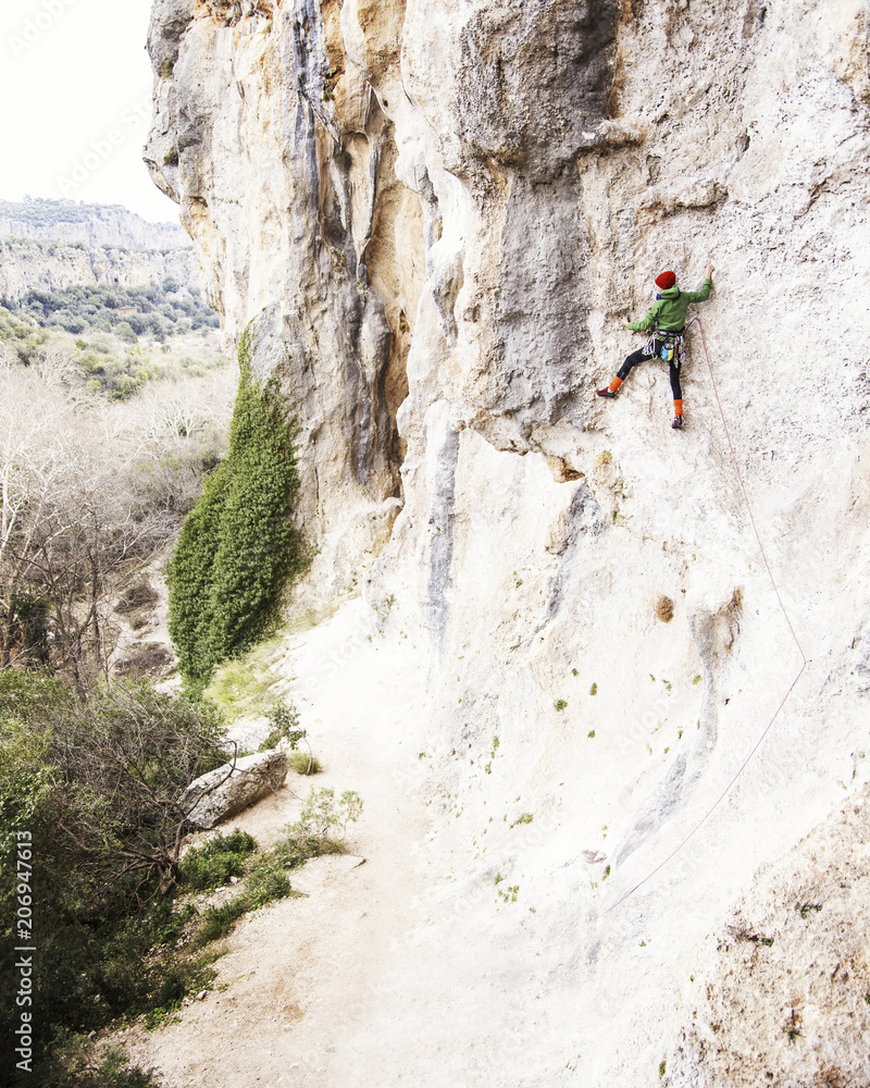 Woman rock climber. Rock climber climbs on a rocky wall. Woman makes hard move. Woman rock climber. Rock climber climbs on a rocky wall. Woman makes hard move.