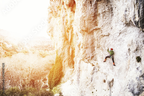 Woman rock climber. Rock climber climbs on a rocky wall. Woman makes hard move.